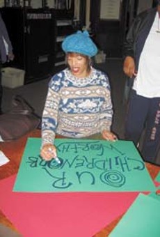 City resident Selina Williams makes a poster at Saturdays rally for city school nurses. The rally was held at New Bethel C.M.E. Church.