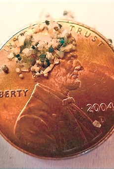 Plastic microbeads as compared to a penny.