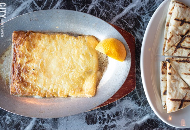 The saganaki appetizer is kefalograviera cheese sautéed in brandy and lemon, set ablaze before your eyes, and served with pita. - PHOTO BY JACOB WALSH