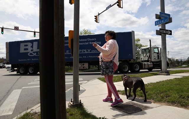 Nancy Hernandez Maciuska, a member of the Lewis Street Committee walks her dog, Hope, along Scio Street as trucks pull off the Inner Loop exit onto Lyndhurst Street. Of city talk to fill in the Inner Loop, she says, "We want to be heard." - PHOTO BY MAX SCHULTE