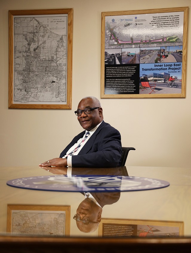 Norman Jones, commissioner of the city’s Department of Environmental Services, was a boy when the Inner Loop was built and is now a key figure in the talks of filling it in. He says the images behind him — a map of Rochester before the Inner Loop and pictures of the development on the filled-in eastern portion — guide him. - PHOTO BY MAX SCHULTE