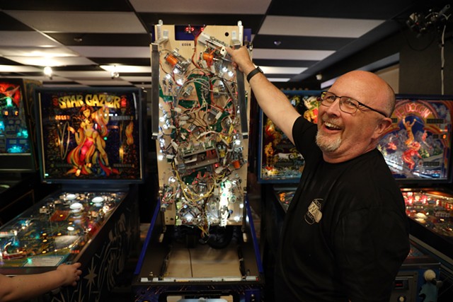 Bruce Nightingale displays the guts of a modern pinball machine. More than half the machines at Rochester Pinball Collective are from his personal collection. - PHOTO BY MAX SCHULTE