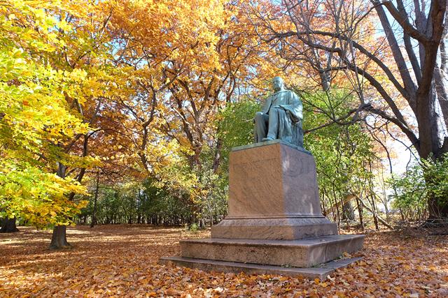 A statue of Edward Mott Moore, who championed the development of a parks system in Rochester, stands at the edge of Genesee Valley Park, in front of a wooded area that the University of Rochester owns and could develop. - PHOTO BY JEREMY MOULE