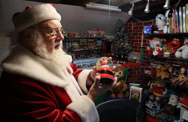 Mike Ihrig greets his virtual visitors against a backdrop of toys, books, snow globes, and animatronic figures that he has amassed over the years. - PHOTO BY MAX SCHULTE