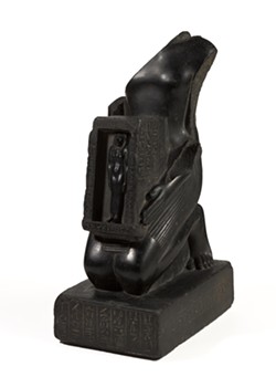 A basalt object labeled "Temple Statue of Pawerem, Priest of Bastet" with its head removed. Curatorial info states this statue was most likely damaged after the 4th century, when there were often attacks on temple statues to disable their pre-Christian purpose. - PHOTO COURTESY BROOKLYN MUSEUM