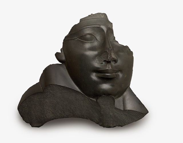 The nose is destroyed on a basalt face and shoulder from an Anthropoid sarcophagus, and the beard of Osiris — a marker of royalty and divinity — has been removed. - PHOTO COURTESY BROOKLYN MUSEUM