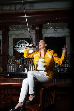 Mel Muscarella channels her inner Freddie Mercury as she sits on the bar at Iron Smoke Distillery. - PROVIDED