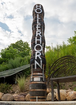 A totem, including whiskey barrels blackened by the 2022 fire, welcomes visitors to the distillery. - PHOTO BY JACOB WALSH