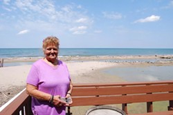 Fran Beth stands in front of the flooding damage on Lake Ontario outside her business, Marge's Lakeside Inn. - VERONICA VOLK.