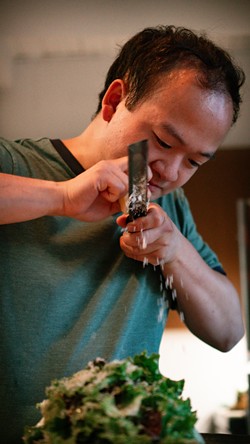 Microclimate owner and operator Anthony Do shaving piave vecchio over a yuzu caesar salad. - PETE WAYNER.