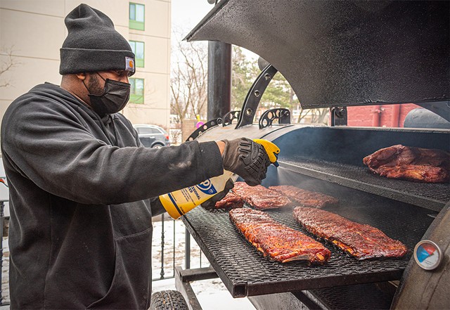 Terrell McLean, the co-owner and chef at Bubby's BBQ, sprays down racks of ribs on his giant smoker, "Goliath."