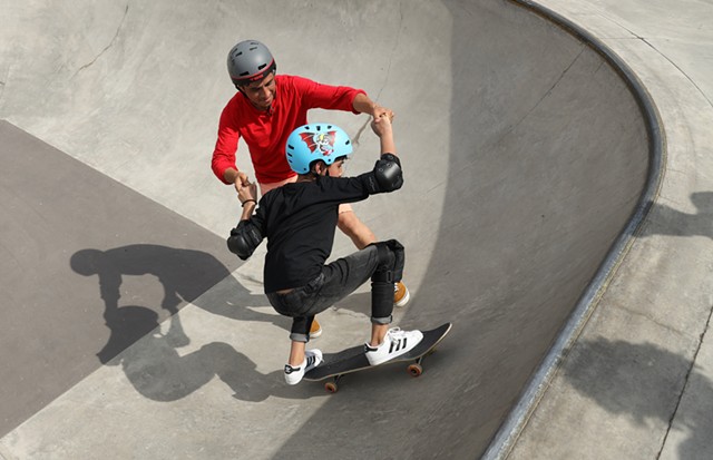 Shabeer, foreground, gets a hand riding the bowl at the ROC City Skatepark from Skateistan instructor Farzad Sharafi.