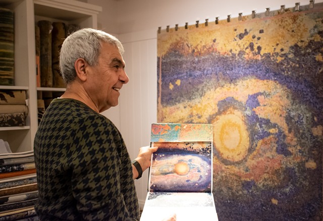 Oriental Rug Mart owner Reza Nejad Sattari compares a photograph by Charles Brian Orner and the art rug made from that work. Sattari works with artists and a team of masterweavers in Nepal to translate art to high-end rugs for his "Art Interpreted" series.